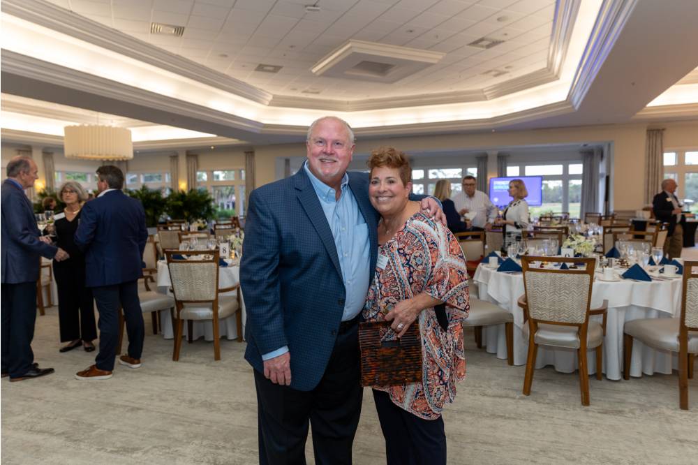 Beth Rinvelt and gentleman guest standing together and smiling at camera